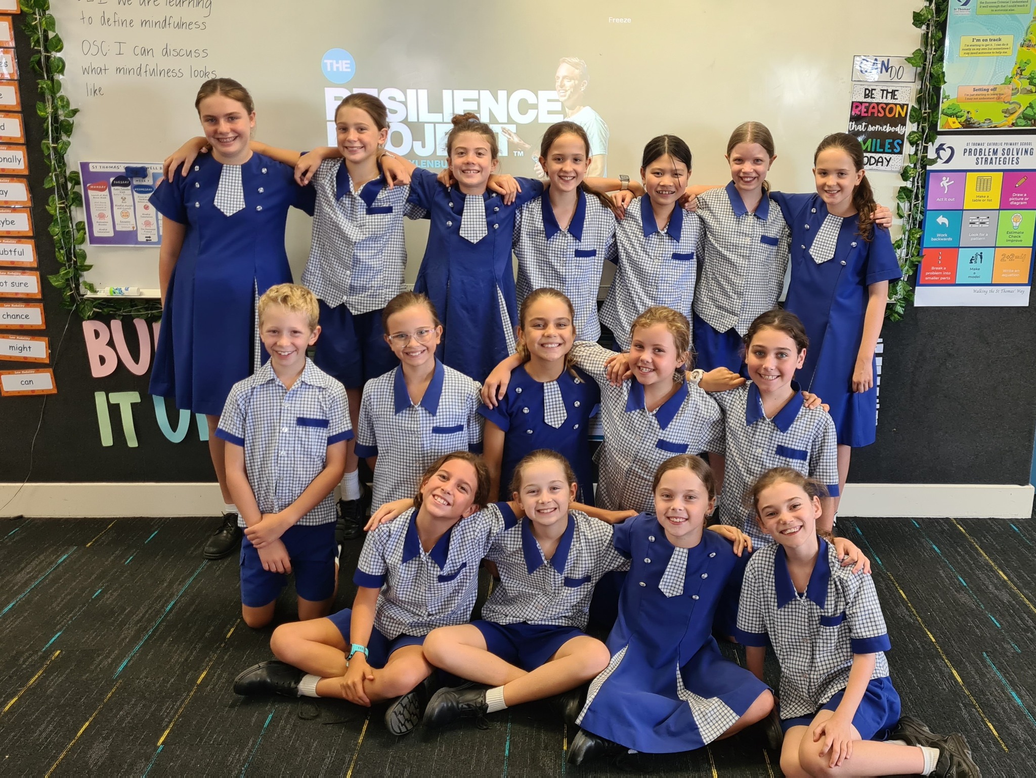 Class group photo of students in school uniform inside a classroom.